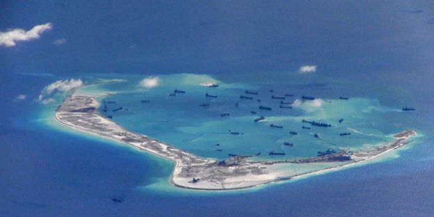 Luftaufnahme: Eine schmale Insel, in der Nähe viele Schiffe