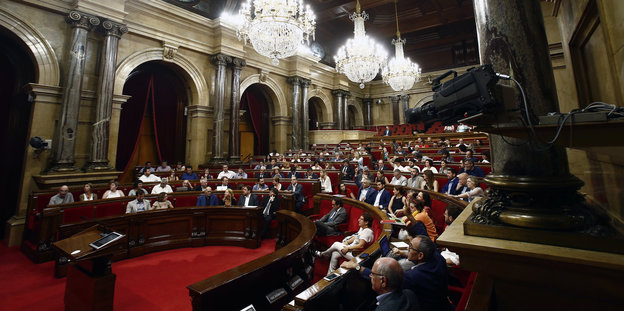 Menschen sitzen auf Holzbänken in einem Parlamentsgebäude