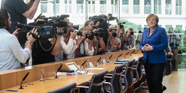 Angela Merkel steht bei der Bundespressekonferenz neben einer Reihe von Fotografen