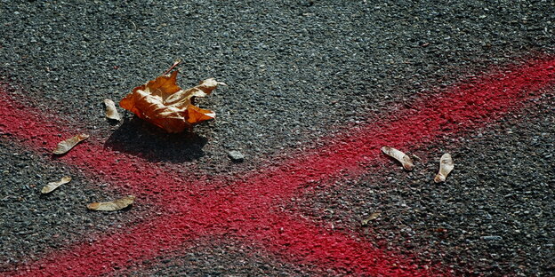 Ein rotes Kreuz ist auf eine Straße gemalt