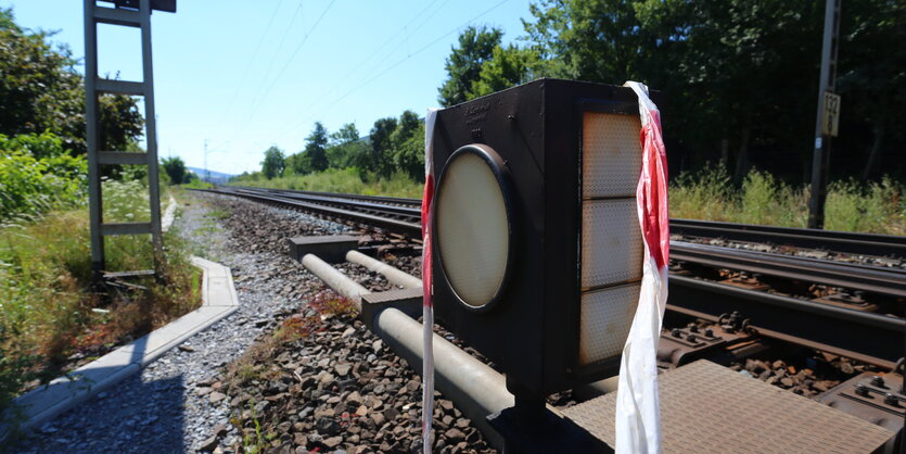 Ein ausgeblichenes Absperrband hängt an Bahnschienen