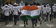 Viele Menschen in weißen T-Shirts von hinten, zwei halten eine Fahne Indiens