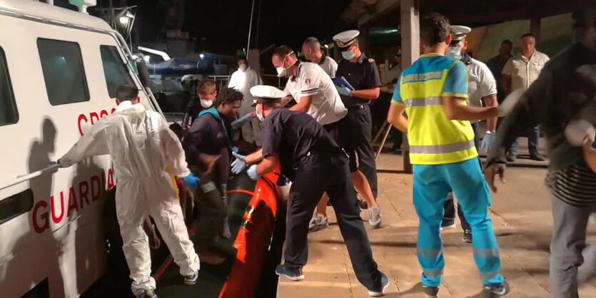 Rettungskräfte helfen einem Mann aus einem Boot an Land