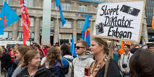 Viele Demonstranten, einer hält ein Schild, auf dem "Stoppt Diktator Erdogan" steht