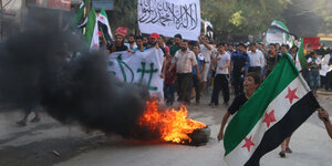 Demonstranten mit Flaggen der Freien Syrischen Armee und brennende Reifen