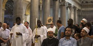 Messdiener laufen durch die Kirche, in der ersten Reihe sitzen Muslime