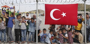 Menschen hinter einem Zaun mit türkischer Flagge