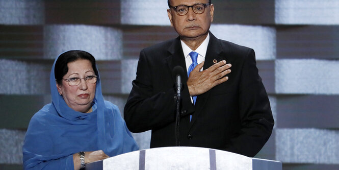 Eine Frau mit Schleier und ein MAnn im Anzug, der seine rechte Hans aufs Herz legt. Es sind Khizr und Ghazala Khan