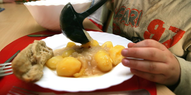 Ein Junge nimmt sich beim Pädagogischen Mittagstisch des Kinderschutzbundes in Schwerin Soße für die Kartoffeln