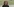 Eine junge Frau mit Locken und Brille steht vor einer grünen Hügellandschaft.