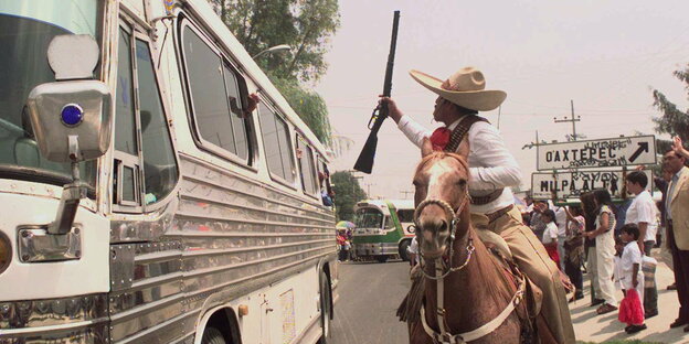 Ein Mann, der wie der revolutionäre Held Emiliano Zapata angezogen ist, reitet auf einem Pferd neben einem Bus in Xochimilco, Mexiko, 1997