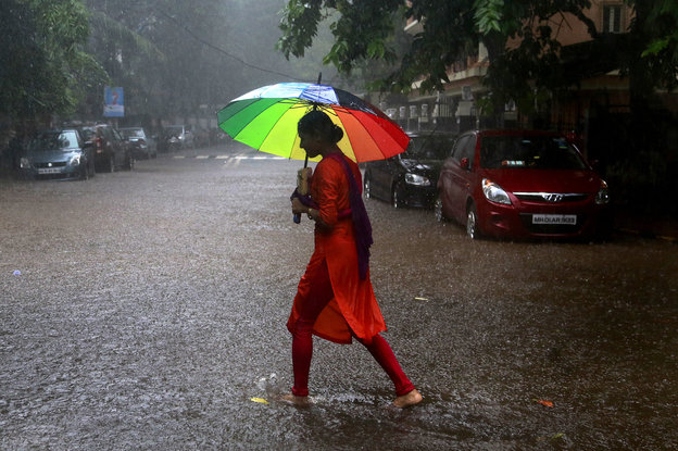 Eine Frau mit einem bunten Regenschirm läuft durch den Regen