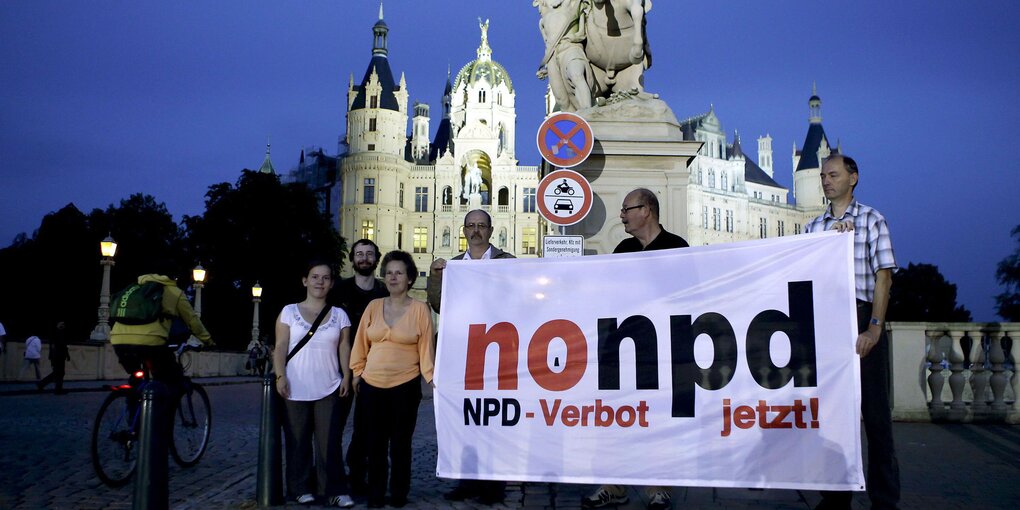 eine kleine Gruppe demonstrierende hält ein no-npd-transparent vor dem schweriner schloss