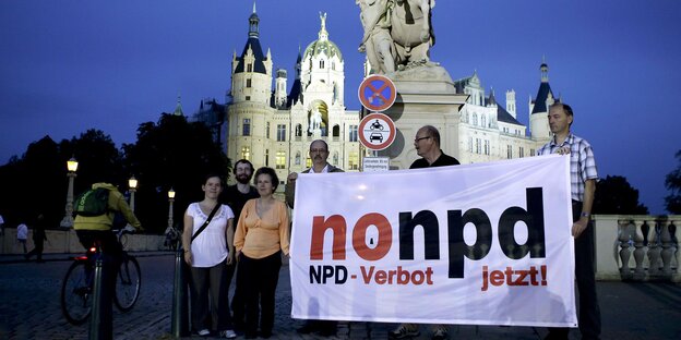 eine kleine Gruppe demonstrierende hält ein no-npd-transparent vor dem schweriner schloss