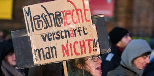 Ein Frau hält auf einer Demo ein Schild hoch, darauf steht: "Menschenrecht verschärft man nicht"