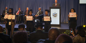 Vier Frauen erinnern mit Schildern während der Präsidentenrede an Zumas Anklage wegen Vergewaltigung.