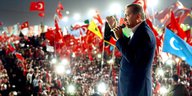 Erdoğan steht mit einem Mikro in der Hand vor einer Menschenmenge