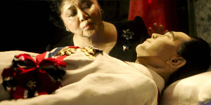 der einbalsamierte Leichnam von Exdiktator Ferdinand Marcos. Hinter der Glasscheibe seine Witwe Imelda, die einen Kussmund macht