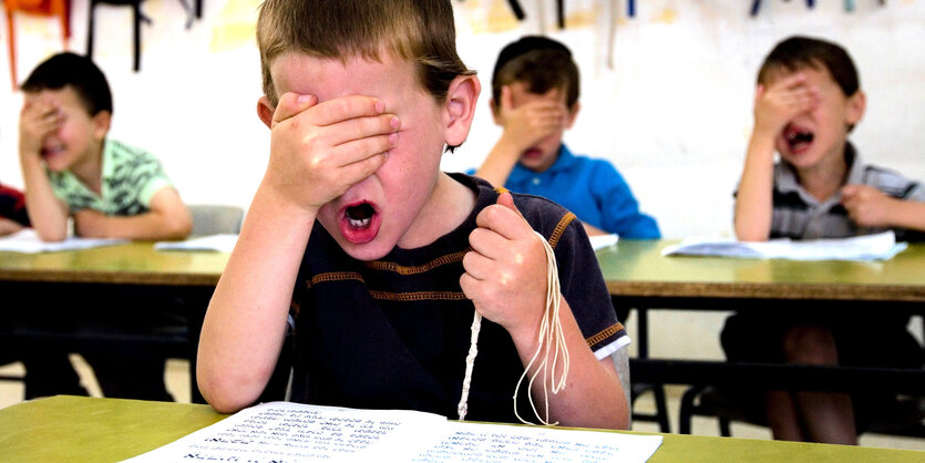 vier Jungen in einer Schule halten sich die Hand vor den Kopf