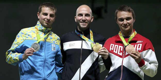 drei Männer mit Medaillen