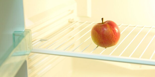 Ein Apfel liegt in einem ansonsten leeren Kühlschrank