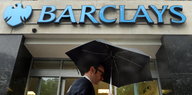 Ein Fußgänger geht mit einem Regenschirm an einer Barclays-Bank vorbei