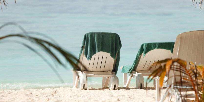 Liegestühle am Strand mit Handtüchern