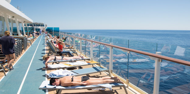 Menschen liegen auf einem Kreuzfahrtschiff auf Sonnenliegen