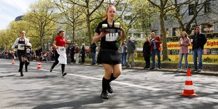 Drei Frauen in Kellneroutfit rennen mit Getränken auf dem Tablett