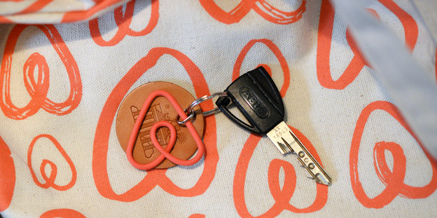 Ein Schlüssel an einem Airbnb-Anhänger liegt auf einem Stück Stoff mit dem Logo der Firma