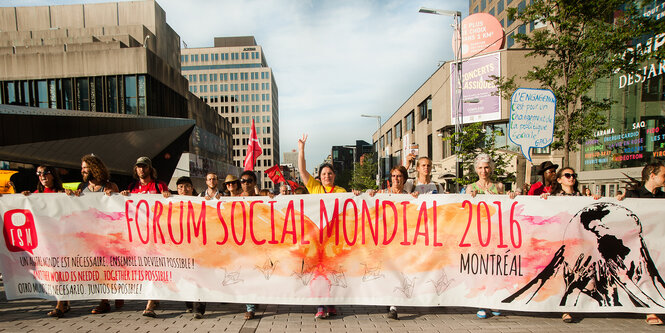 Menschen tragen ein Banner durch die Straßen einer Stadt