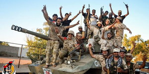 US-Unterstützungstruppen feiern die Rückeroberung von Sirte mit erhobenen Armen auf einem Panzer