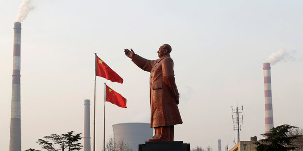 Eine Statue von Mao Zedong steht vor den qualmenden Kaminen einer Stahlfabrik in Wuhan, China.