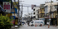 Eine leere, abgesperrte Straße in einer thailändischen Stadt, ein weißer Lieferwagen steht in der Mitte