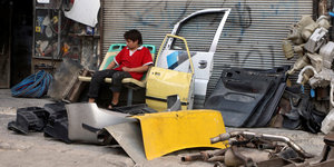 Ein Junge sitzt zwischen Autoersatzteilen