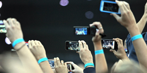 Viele Menschen halten ihre Smartphones in die Höhe und filmen