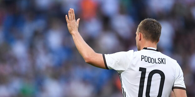 Lukas Podolski im Trikot der Nationalmannschaft von hinten und mit erhobenem Arm