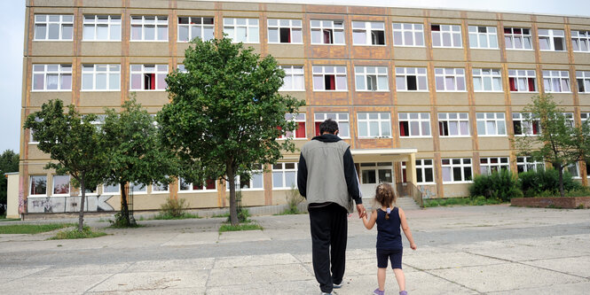 Ein Vater mit Tochter vor einem Plattenbau, der ein Flüchtlingsheim in Berlin-Hellersdorf ist