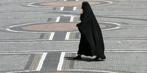 Eine Frau in einer Burka geht über den Odeonsplatz in München