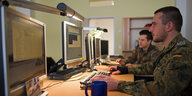 Zwei Soldaten der Bundeswehr blicken auf Computerbildschirme.