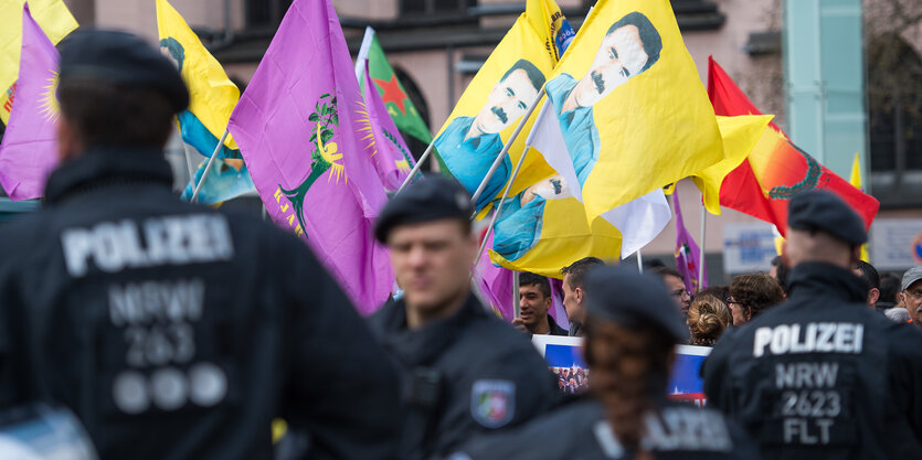 Polizisten, im Hintergrund Demo mit Fahnen