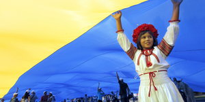 Mädchen in Tracht unter einer riesigen ukrainischen Flagge