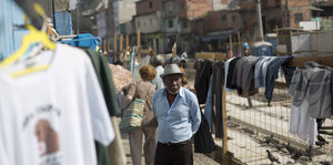 Ein Straßenhändler steht zwischen T-Shirts