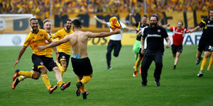 Jubelnde Fans und Fußballer in gelb-schwarzer Kleidung