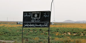 ein Schild des IS in grüner Landschaft