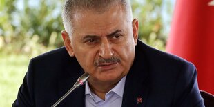 Binali Yıldırım an einem Mikro, hinter ihm eine Wiese und Wasser