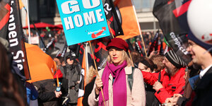 Eine Frau hält ein AfD-Transparent inmitten einer TTP-Demo hoch