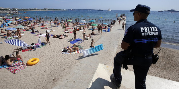 Ein uniformierter Polizist beobachtet den Strand von Cannes