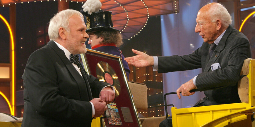 Walter Scheel sitzt in einer gelben Kutsche in einem TV-Studio