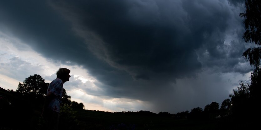 Ein Mann steht unter dunklem Wolkenhimmel